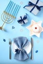 Jewish holiday Hanukkah concept. Hanukkah food jelly donut, plate with napkin and cutlery, menorah with candles, gift boxes, Royalty Free Stock Photo