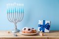 Jewish holiday Hanukkah concept with menorah, traditional donuts and gift box on wooden table Royalty Free Stock Photo