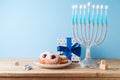 Jewish holiday Hanukkah concept with menorah, traditional donuts and gift box on wooden table Royalty Free Stock Photo