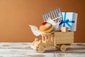 Jewish holiday Hanukkah concept with traditional donuts, menorah and gift box on toy truck