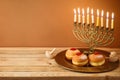 Jewish holiday Hanukkah concept with vintage menorah, candles and traditional donuts on wooden table Royalty Free Stock Photo