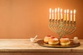 Jewish holiday Hanukkah concept with vintage menorah, candles and traditional donuts on wooden table