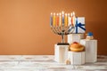 Jewish holiday Hanukkah creative concept with menorah, traditional donuts and gift box on podium on wooden table Royalty Free Stock Photo