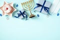 Jewish holiday Hanukkah flat lay composition with gold menorah, gift boxes, jelly donut, candles on pastel blue background Royalty Free Stock Photo