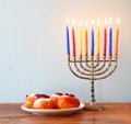 Jewish holiday Hanukkah with menorah, doughnuts over wooden table. retro filtered image Royalty Free Stock Photo