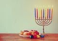 Jewish holiday Hanukkah with menorah, doughnuts over wooden table. retro filtered image Royalty Free Stock Photo