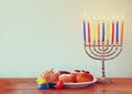 Jewish holiday Hanukkah with menorah, doughnuts over wooden table. retro filtered image. Royalty Free Stock Photo