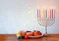 Jewish holiday Hanukkah with menorah, doughnuts over wooden table. retro filtered image Royalty Free Stock Photo
