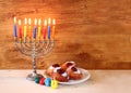 Jewish holiday Hanukkah with menorah, doughnuts over wooden table. retro filtered image. Royalty Free Stock Photo