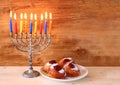 Jewish holiday Hanukkah with menorah, doughnuts over wooden table. retro filtered image. Royalty Free Stock Photo