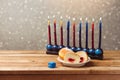 Jewish holiday hanukkah with sufganiyah and menorah on wooden table over bokeh background Royalty Free Stock Photo