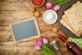 Jewish holiday Passover background with matzo, seder plate, wine, tulip flowers and chalkboard on wooden table Royalty Free Stock Photo