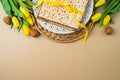 Jewish holiday Passover celebration concept with matzah, seder plate and yellow tulip flowers on modern background. Flat lay, top
