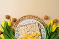 Jewish holiday Passover concept with matzah, seder plate and yellow tulip flowers on modern background
