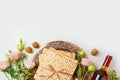 Jewish holiday Passover concept with matzah, seder plate, spring flowers and wine bottle on white background. Top view, flat lay