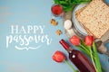 Jewish holiday Passover Pesah greeting card with seder plate, matzoh and flowers over blue background