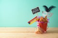 Jewish holiday Purim background with bucket, carnival mask, noisemaker and hamantaschen cookies on wooden table