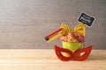 Jewish holiday Purim background with bucket, carnival mask, noisemaker and hamantaschen cookies on wooden table