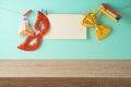 Jewish Holiday Purim holiday background with empty wooden table, paper note, carnival mask and cookie