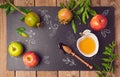 Jewish holiday Rosh Hashana background with apples, pomegranate and honey on blackboard. View from above.