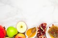 Jewish holiday Rosh Hashana background with honey, pomegranate and apples on white marble table. flat lay