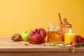 Jewish holiday Rosh Hashana concept with honey jar, apple and pomegranate on wooden table over yellow background Royalty Free Stock Photo