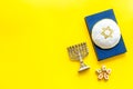 Jewish Kippah Yarmulkes hats with Star of David on Prayer book with menorah. Religion Judaisim symbols on yellow table