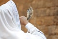 Jewish man blowing shofar on Rosh Hashanah outdoors. Wearing tallit with words Blessed Are You, Lord Our God, King Of The Universe