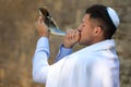 Jewish man in kippah and tallit blowing shofar. Rosh Hashanah celebration