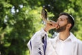 Jewish man in kippah and tallit blowing shofar. Rosh Hashanah celebration