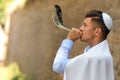 Jewish man in kippah and tallit blowing shofar. Rosh Hashanah