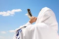 Jewish man in tallit blowing shofar outdoors. Rosh Hashanah celebration