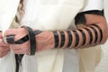 Jewish Man wrapped in tefillin pray . A religious orthodox with arm-tefillin on his left hand prays