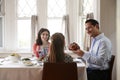 Jewish man holding challah bread at Shabbat meal with family