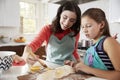 Jewish mother and daughter glazing dough for challah bread