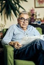 Jewish senior with glasses in the armchair reading a torah book