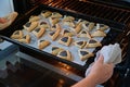 Jewish woman hands taking out baked Hamantash cookies from kitchen oven