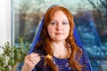 A Jewish woman with her head covered in a blue cape at the Passover Seder table eats haroset.