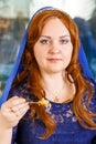 A Jewish woman with her head covered in a blue cape at the Passover Seder table eats haroset.