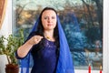 A Jewish woman with her head covered in a blue cape at the Passover Seder table eats haroset.