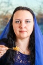 A Jewish woman with her head covered in a blue cape at the Passover Seder table eats haroset.