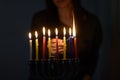 Jewish Woman lighting Hanukkah Candles in a menorah.