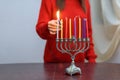 Jewish Woman lighting Hanukkah Candles in a menorah. Royalty Free Stock Photo