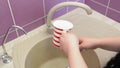 a Jewish woman washes her hands from a mug above the sink, alternately pouring netilat yadaim on each hand.