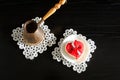 Jezva with coffee, saucer with red heart-shaped gingerbread on a black wooden background.