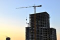 Jib construction tower crane and new residential buildings at a construction site on the sunset and blue sky background Royalty Free Stock Photo