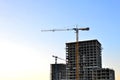 Jib construction tower crane and new residential buildings at a construction site on the sunset and blue sky background Royalty Free Stock Photo