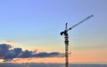 Jib construction tower crane and new residential buildings at a construction site on the sunset and blue sky background Royalty Free Stock Photo