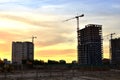 Jib construction tower crane and new residential buildings at a construction site on the sunset and blue sky background Royalty Free Stock Photo