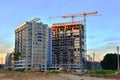 Jib construction tower crane and new residential buildings at a construction site on the sunset and blue sky background Royalty Free Stock Photo